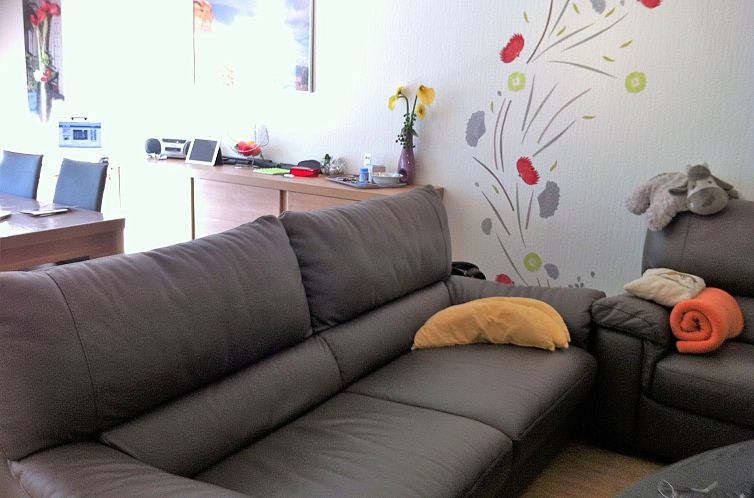 Cozy living room of Appartement Wohnung 'Wie zu Hause' in Middelkerke, Belgian coast, with comfortable sofa and colorful wall decoration.