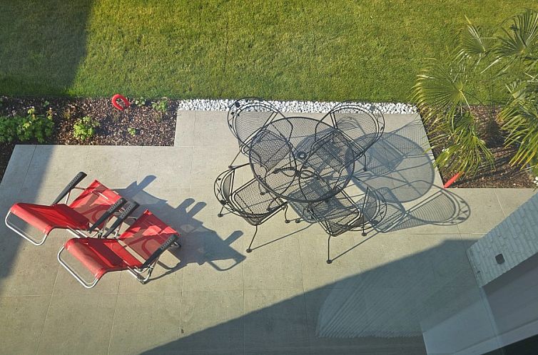 't Zeehuisje in Westende: Sonnige Terrasse mit Gartenmoebeln und Liegestuehlen zum Entspannen an der belgischen Kueste.