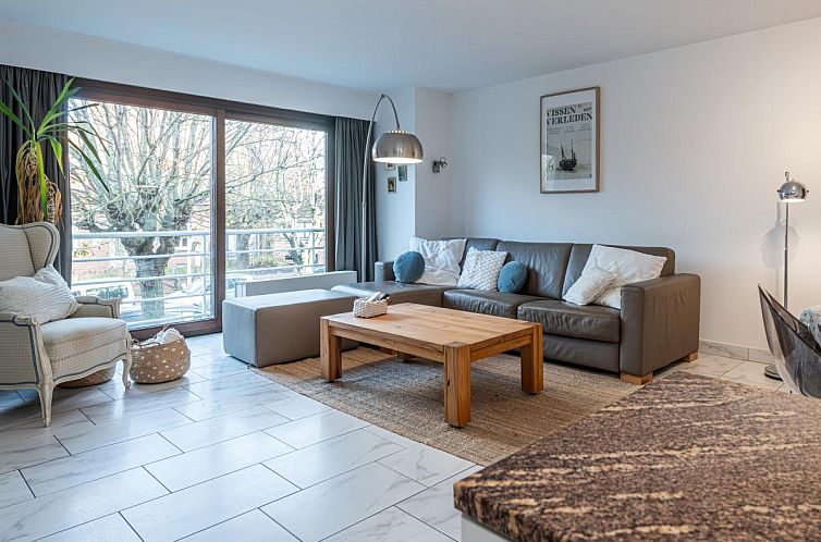 Cozy living room in vacation home Reigersnest, Nieuwpoort, Belgian coast, with comfortable sitting area and view of green surroundings.