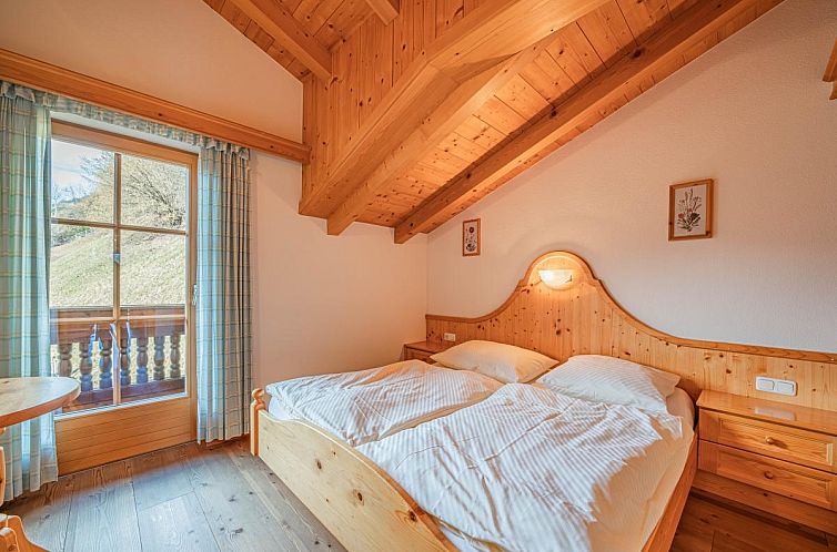 Schlafzimmer des Andre XL Ferienhauses in Wald im Pinzgau, Salzburg, mit rustikalem Holzdesign und schoenem Blick auf die Umgebung.