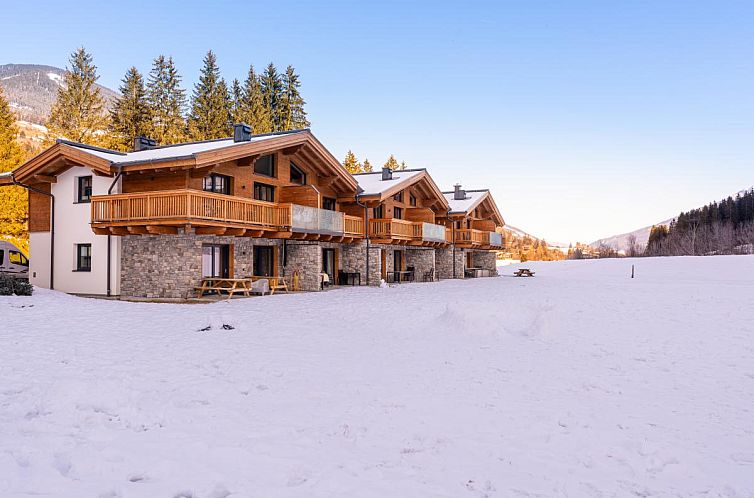 Chalet Pinzgau Lodge 2E in Wald, Salzburg, omringd door sneeuw en bergen, biedt een idyllisch winterverblijf met rustieke houten details.
