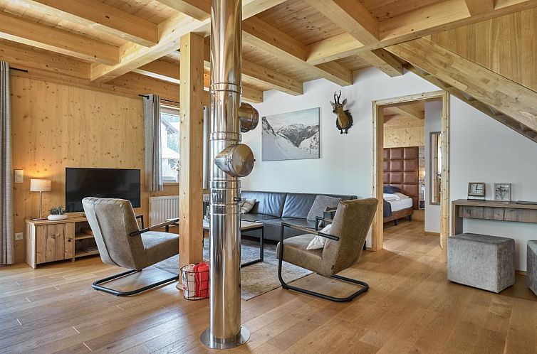 Das Mur-Chalet St. Michael L in Salzburg bietet ein warmes Wohnzimmer mit Holzoberflaechen und modernen Moebeln.