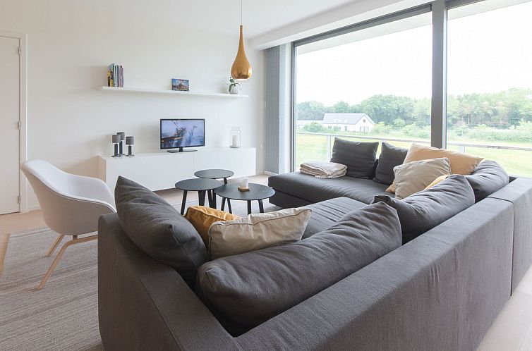 Bright living room of Apartment Duinenhof 18 overlooking green surroundings in De Haan, Belgian coast, ideal for a relaxing stay.