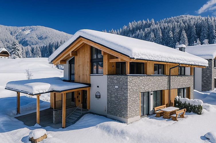 Erleben Sie den winterlichen Charme des Almchalet Alpenglueck, ein gemuetliches Ferienhaus in Sankt Lambrecht, Steiermark, umgeben von Schnee und Bergen.