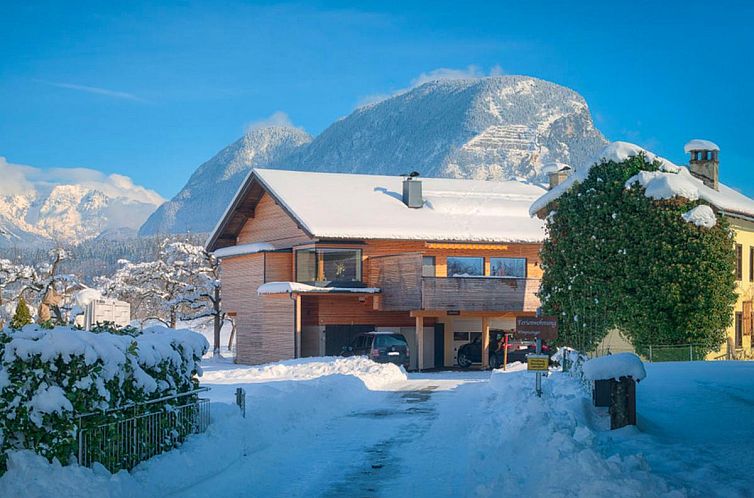 Schnee bedeckt das Ferienhaus Innradweg in Angath, Tirol, mit den majestaetischen Bergen im Hintergrund.