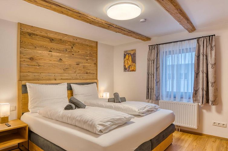 Rustieke slaapkamer van Chalet Berggluck in Sellrain, Tirol, met warme houten accenten en een uitnodigend tweepersoonsbed.