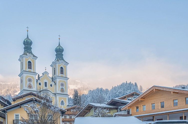 Discover Das Fritz in Hopfgarten im Brixental, Tyrol, a vacation home overlooking a picturesque church and winter landscape.