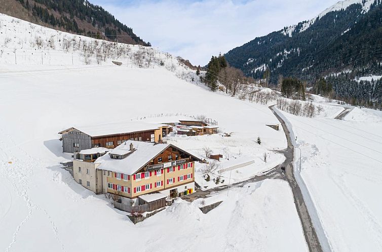 Gemuetliches Gaestehaus Walch III in Kloesterle, Vorarlberg, umgeben von einer winterlichen Berglandschaft.