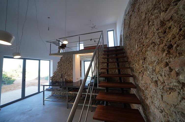 Stylish loft of Cottage in Lagoa, located in Algarve, Portugal, with modern staircase and characteristic stone walls.