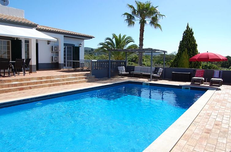 Geniet van de zon op het terras van Vakantiehuis in Santa Barbara de Nexe, Algarve, met zwembad en groene omgeving.