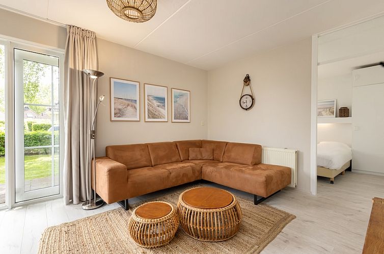 Gezellige woonkamer van Wellness Wiid Plus 8 bungalow in Earnewald, met comfortabele bank en kunst aan de muur, nabij de Friese meren.