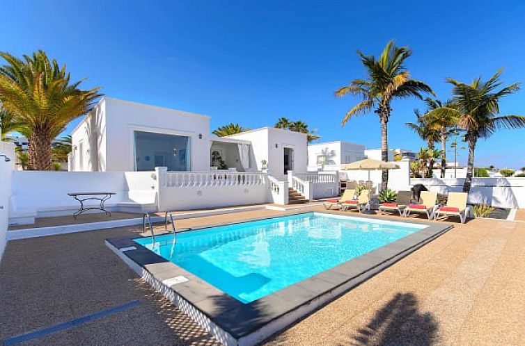 Vakantieverblijf Villa del Puerto in Puerto del Carmen, Spanje, met helderblauw zwembad en ruime buitenruimte met ligstoelen.