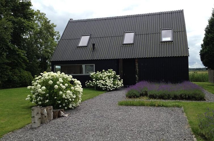 Vakantiehuisje in Midlaren omgeven door groene natuur en bloeiende struiken, ideaal gelegen in Noord Drenthe voor een ontspannen verblijf.