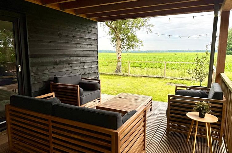 Geniet van het uitzicht vanaf de veranda van Vakantiehuisje in Odoornerveen, Drenthe, met comfortabele zitplekken en groene velden.