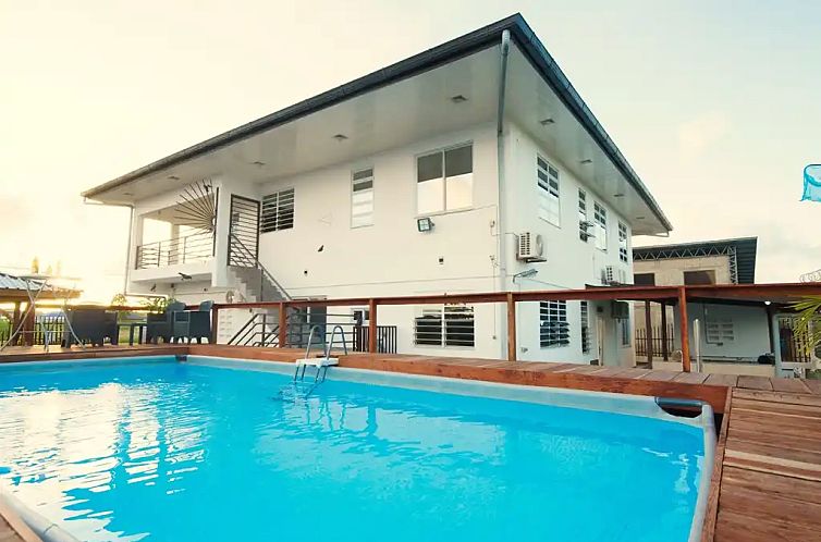Ontspan in Villa Palm Beach, een vakantiehuis in Paramaribo, Suriname, met een uitnodigend zwembad en een ruim terras voor ultiem comfort.