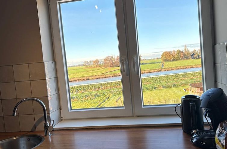 Uitzicht vanuit de keuken van Vakantiehuisje in Schildwolde, Groningen, met weidse velden en een rivier in Noordoost Groningen.