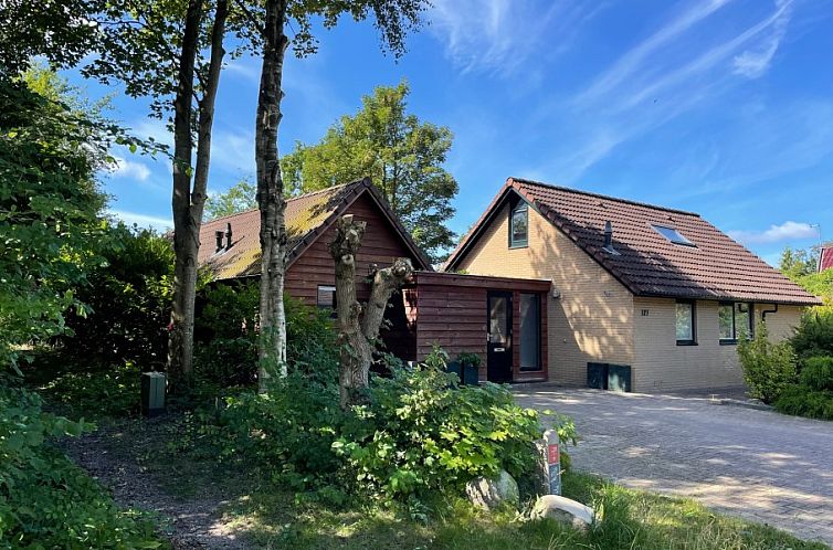 Robbenoort 127, 'Lauwie' vakantiehuis in Lauwersoog, Groningen, omgeven door groene natuur en rustieke architectuur.