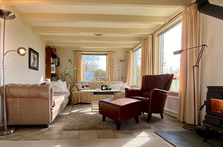 Gezellige woonkamer in Vakantiehuisje in Zoutkamp, Noordwest Groningen met comfortabele zitplaatsen en uitzicht op de natuur.
