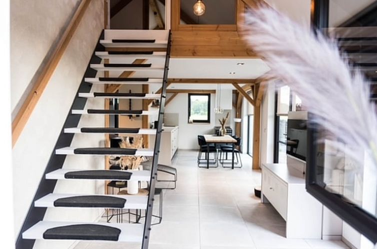 Moderne binnenruimte met houten trap in Vakantiehuisje in Velden, Noord Limburg.