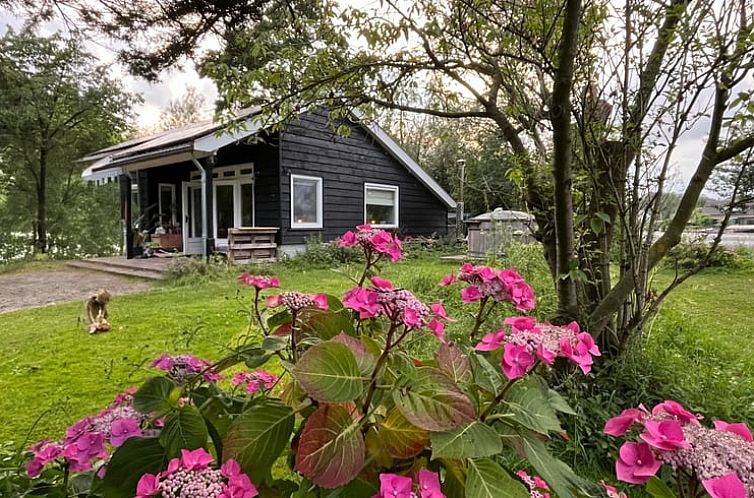 Vakantiehuis in Nigtevecht, Utrecht noord, omgeven door kleurrijke bloemen en groene natuur.