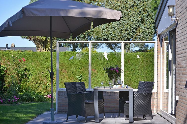 Zonnige tuin met terras en parasol bij vakantiehuis Saturnuslaan 14 Rancho Grande in Kamperland, Noord-Beveland, Zeeland.