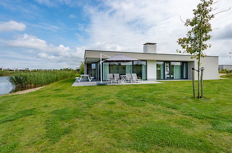 Waterline 01 | De Groote Duynen Bungalow in Kamperland, mit Blick auf gruenen Garten und Wasser.