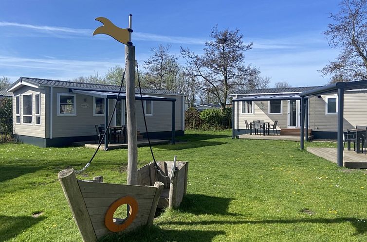 Chalet bij Camping de Duinhoeve in Burgh-Haamstede met groene omgeving en speeltoestel op Schouwen-Duiveland.