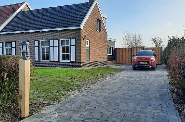 Vooraanzicht van Huisje in Stavenisse, een vakantiehuis in Tholen, Zeeland, met een oprijlaan en auto.