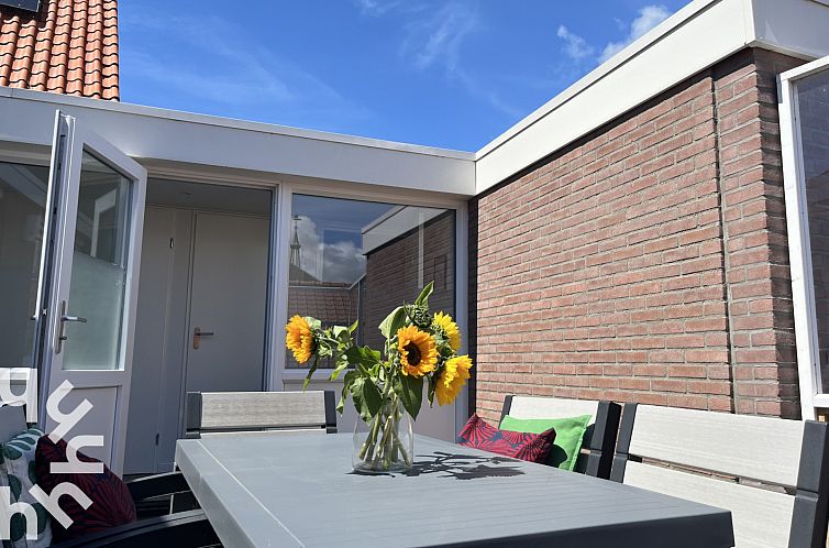 Terrace of vacation home ZE927 in Westkapelle, Walcheren, with sunflowers and blue sky.