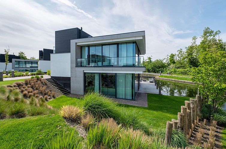 Modern Watervilla 10 in Arnemuiden, Walcheren, Zeeland with glass facade and water views, ideal vacation home for nature lovers.