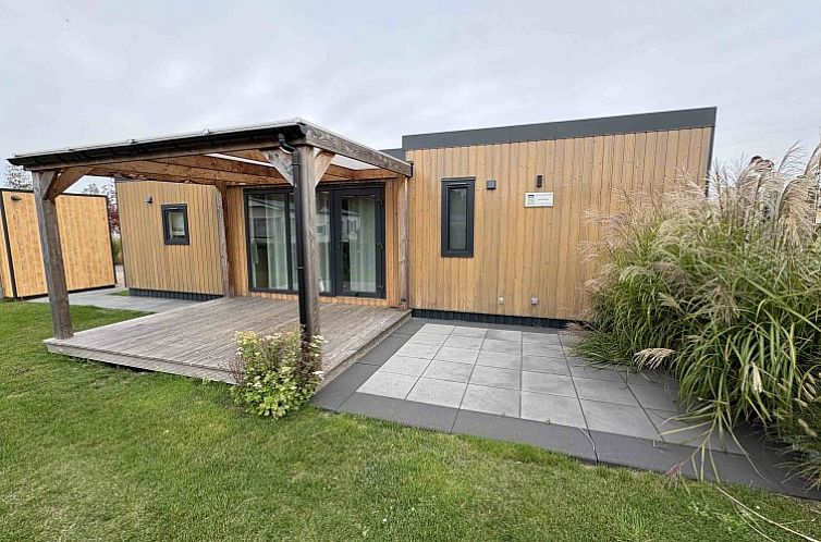 Chalet 165, een charmant vakantiehuis in Koudekerke-Dishoek, Walcheren, Zeeland, met een uitnodigende veranda en omgeven door groene natuur.