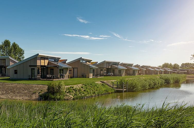 Zeemelde 6 bungalow in Breskens, Zeeuws-Vlaanderen, Zeeland overlooking serene waterfront and green surroundings.