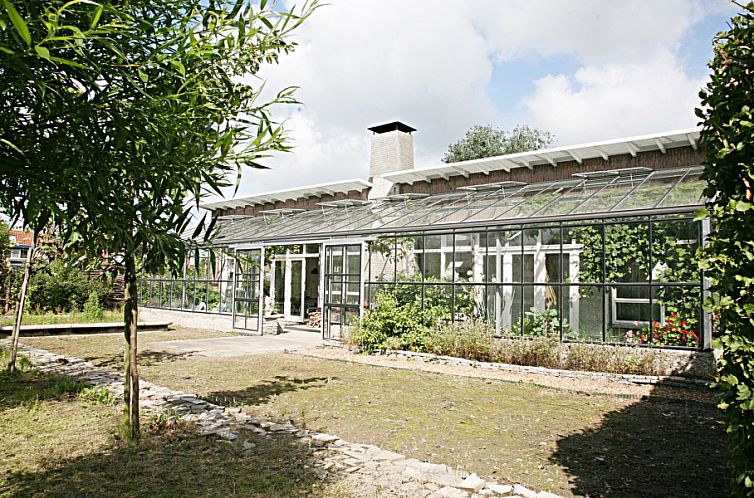 Eko Zonnehuis bungalow in Schoondijke met glazen serre en groene tuin in Zeeuws-Vlaanderen, Zeeland.