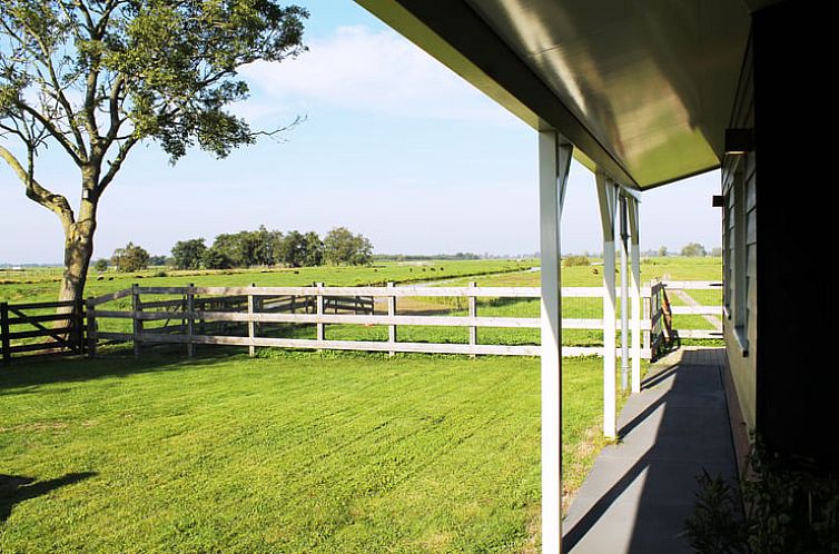 Veranda van Vakantiehuis in Stolwijk met uitzicht op groene velden in Alblasserwaard, Zuid-Holland.