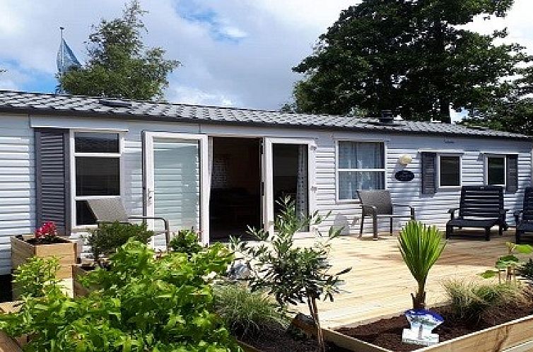 Chalet Sunrise met prive strandtuin in Ouddorp, Zeeland, biedt een zonnig terras met comfortabele ligstoelen en groen uitzicht.