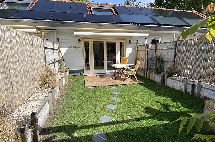 Sunny terrace at VZ991 Holiday home in Ouddorp, South Holland, with comfortable chairs and green surroundings.
