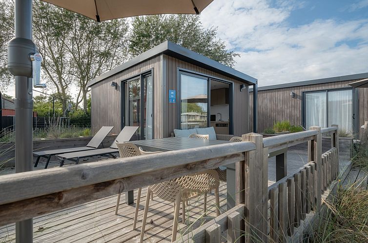 Veranda of Hotelchalet Westerduin in Ouddorp, Goeree-Overflakkee with comfortable deck chairs and dining table.