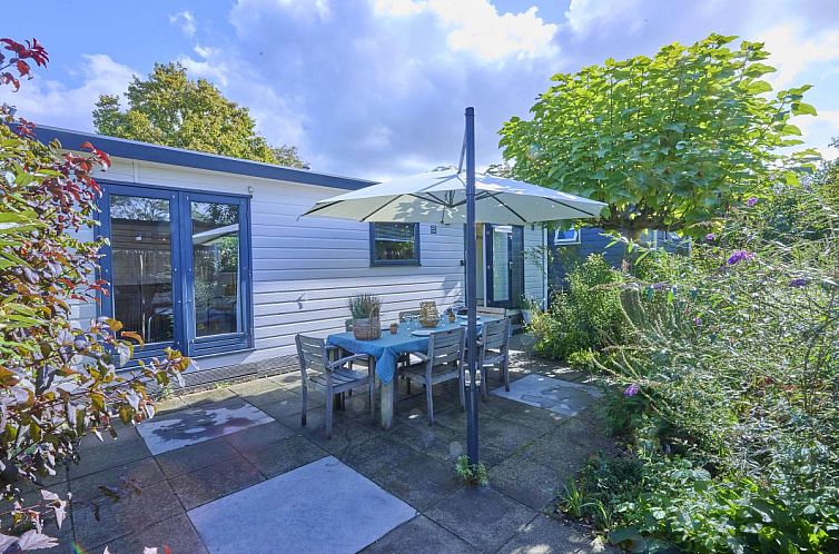 Veranda of Chalet Sea Birds in Goedereede, Goeree-Overflakkee, with garden furniture and parasol for a relaxing vacation.
