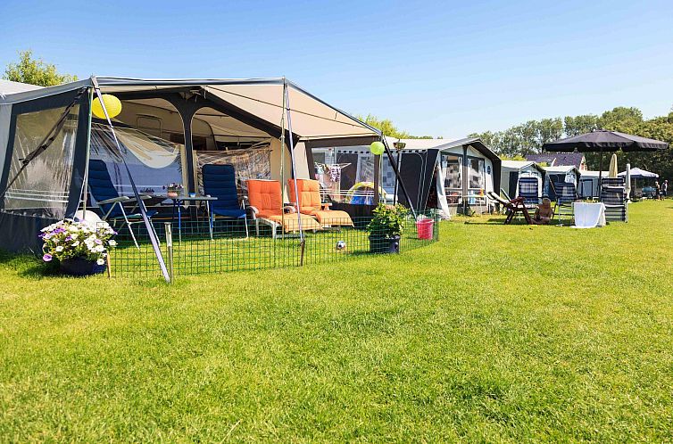 Geniet van de Kampeerplaats Comfort in Noordwijk aan de Noordzeekust, Zuid-Holland, met een zonnig terras en groene omgeving.