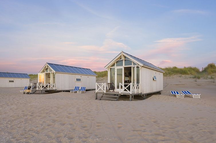 Haagse Strandhuisjes 5 in Kijkduin, Noordzeekust, vakantiehuis met veranda op het strand bij zonsondergang.