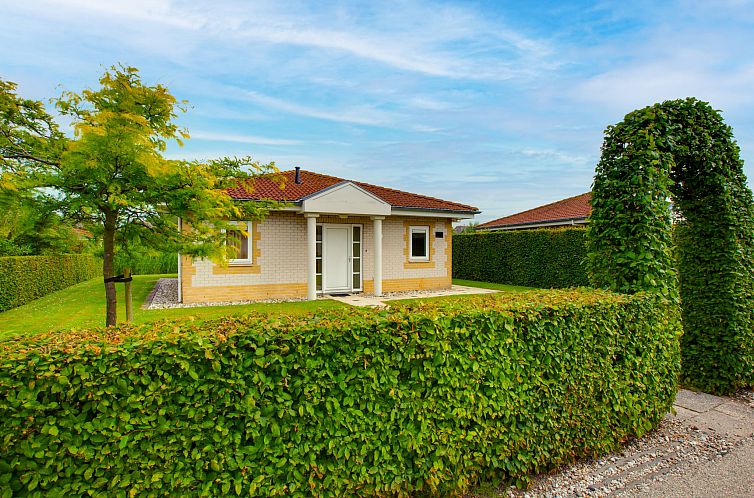 Vacation home Citta Romana in Hellevoetsluis, South Holland with green hedge and blue sky.
